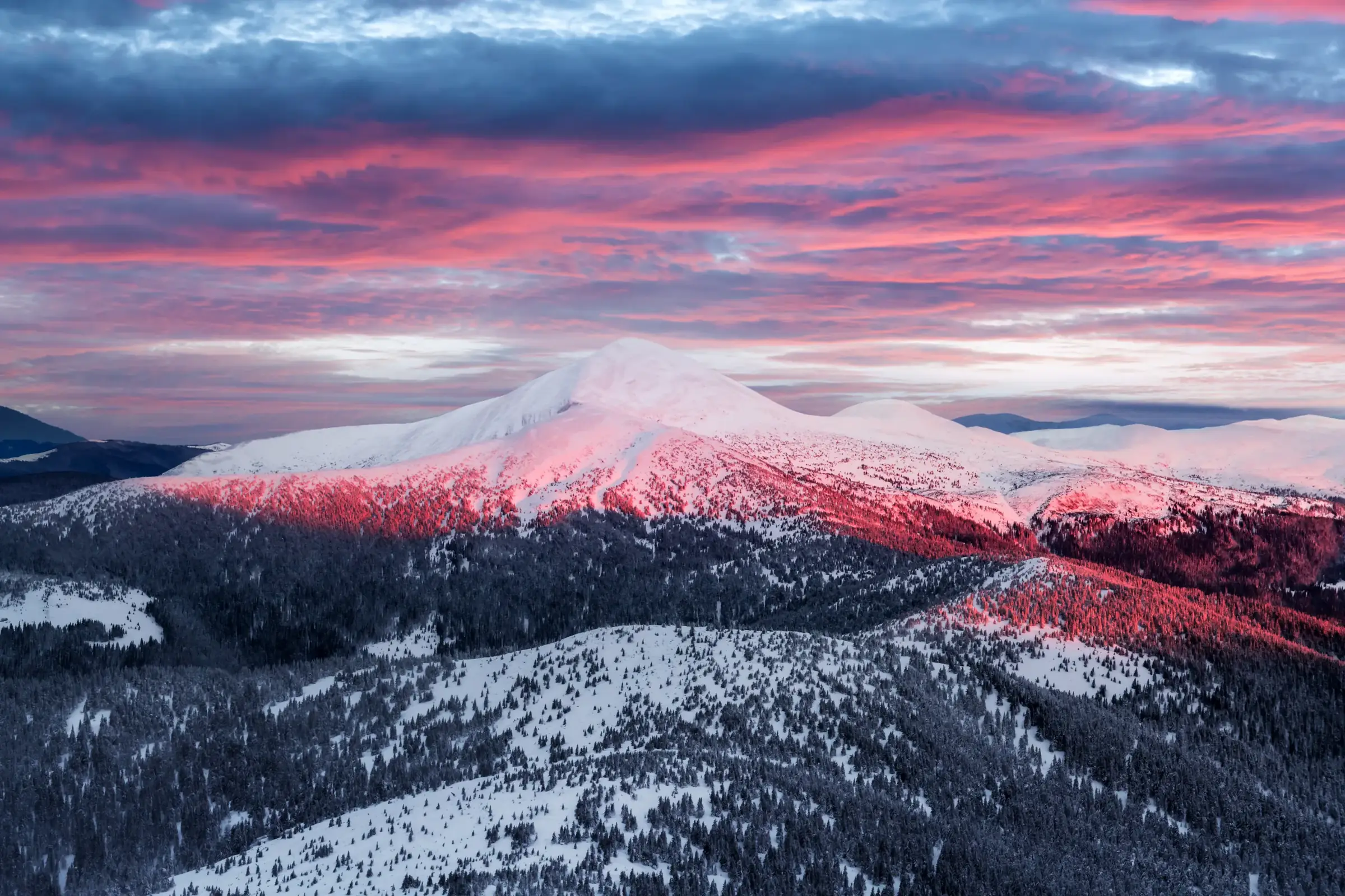 Snow-covered mountains under pink clouds at sunrise